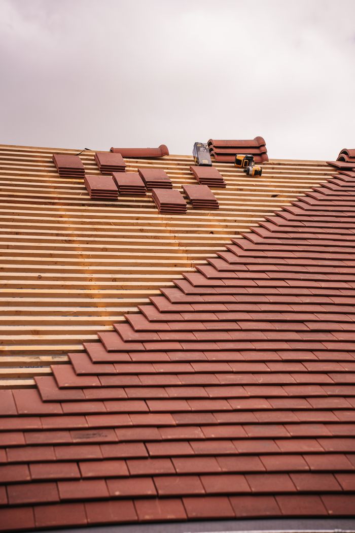 Mastering the First Impression: Your intriguing post title goes here Partial installation of a terracotta tile roof on a building in progress.